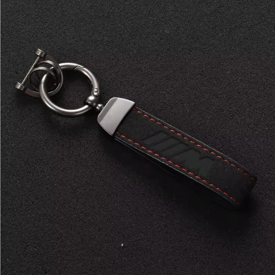 Premium black leather M-logo keychain featuring red stitching and durable metal hardware, ideal for car enthusiasts.
